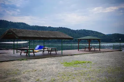 a picnic area with tables and umbrellas next to the water at Hotel Łaziska in Czchów