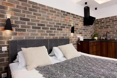 a bedroom with a brick wall and a bed with pillows at Apartament Francuzka in Kraków