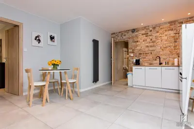 a kitchen with a table and chairs and a brick wall at Apartament Francuzka in Kraków