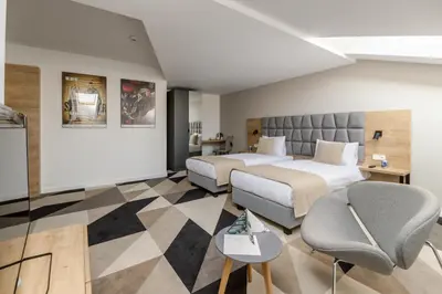 a hotel room with two beds and a chair at Lwowska 1 in Kraków