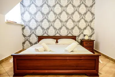 a bedroom with a large bed with white sheets at Dworek Emilli in Wieliczka