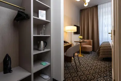 a room with a bed and a desk in a hotel room at Hotel Palladian in Kraków