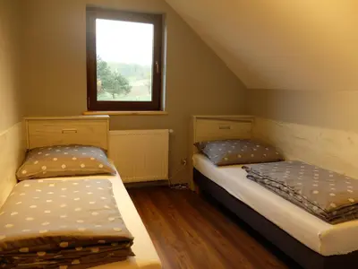 two beds in a small room with a window at Apartament Pozytywka in Tenczynek