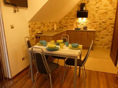 a kitchen with a wooden table and chairs at Apartament Pozytywka in Tenczynek