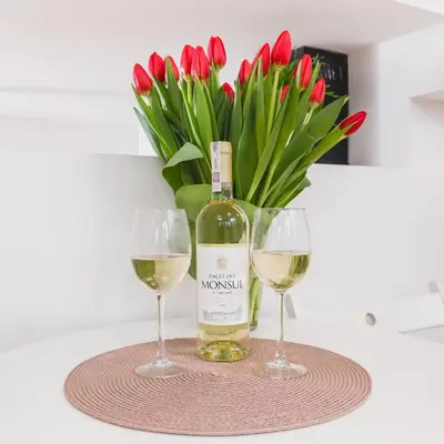 a bottle of wine and two glasses on a table with red tulips at Flower Residence in Kraków