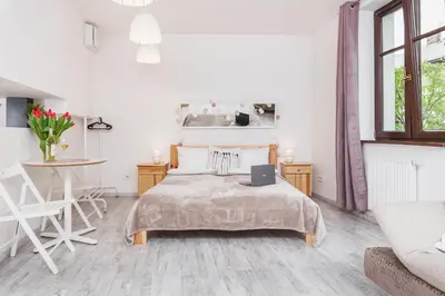 a white bedroom with a bed with a laptop on it at Flower Residence in Kraków