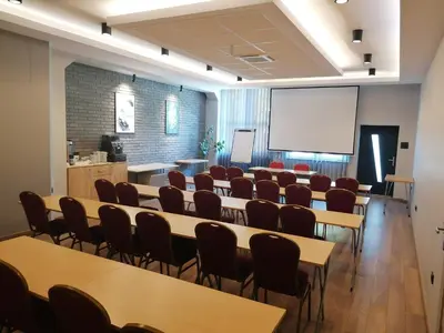 a room with tables and chairs and a white screen at Hotel Zakliki in Kraków
