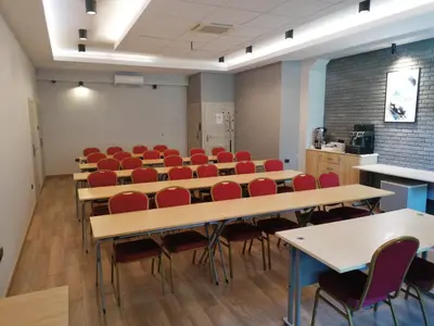 a classroom with tables and red chairs in a room at Hotel Zakliki in Kraków