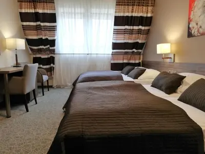 a hotel room with three beds and a desk at Hotel Zakliki in Kraków