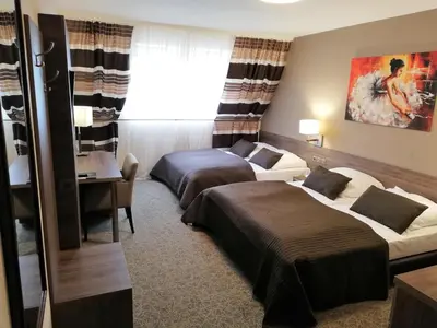 a hotel room with two beds and a desk at Hotel Zakliki in Kraków