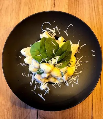 a black plate of food on a wooden table at Hotel Zakliki in Kraków