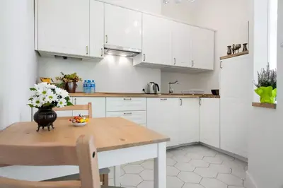 a kitchen with white cabinets and a wooden table at Zwierzyniecka Old Town Apartments by Otium in Kraków
