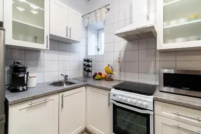 a kitchen with white cabinets and a stove top oven at Horizon Apartments - Plac Nowy in Kraków