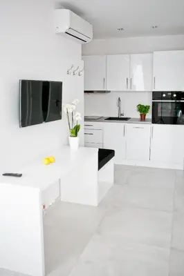 a white kitchen with white cabinets and a tv at Elegant City Center Apartment 7A in Kraków