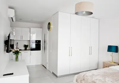 a white kitchen with white cabinets and a bed at Elegant City Center Apartment 7A in Kraków