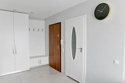 a hallway with a door and a clock on the wall at Elegant City Center Apartment 7B in Kraków