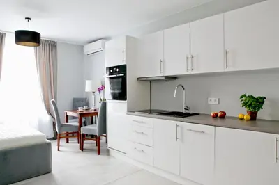 a white kitchen with white cabinets and a table at Elegant City Center Apartment 7B in Kraków