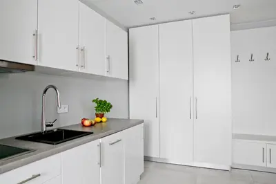 a white kitchen with white cabinets and a sink at Elegant City Center Apartment 7B in Kraków