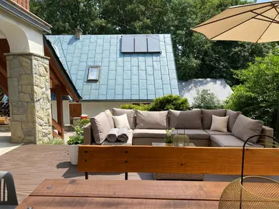 a wooden deck with a couch and tables and umbrellas at Ośrodek Sportowo-Rekreacyjny Słoneczny in Mszana Dolna