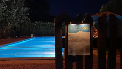 a fence with an umbrella and a swimming pool at night at Ośrodek Sportowo-Rekreacyjny Słoneczny in Mszana Dolna