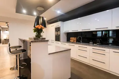 a kitchen with white cabinets and a counter with a vase of flowers at Kings City - Skawińska Apartment in Kraków