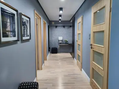 a hallway with blue walls and wooden doors at Kings City - Skawińska Apartment in Kraków