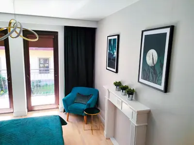 a living room with a blue chair and a window at Kings City - Skawińska Apartment in Kraków