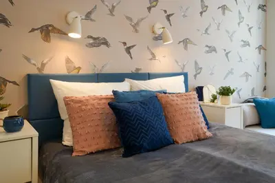 a bedroom with a bed with birds on the wall at Avium Old Town Apartments in Kraków