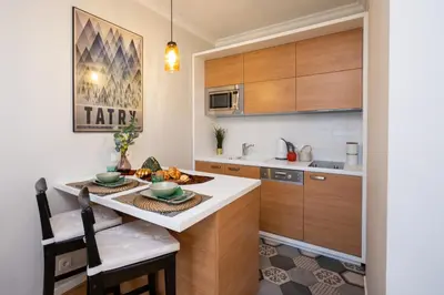 a kitchen with wooden cabinets and a table with two chairs at Avium Old Town Apartments in Kraków