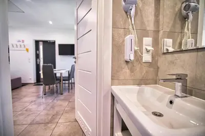 a bathroom with a sink and a room with a table at Apartamenty i Domki u Basi in Zator