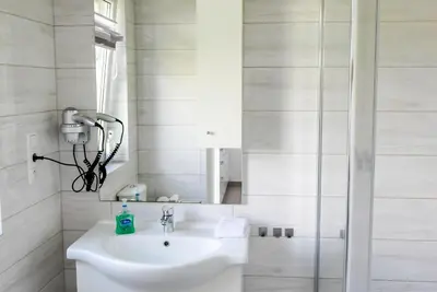 a white bathroom with a sink and a mirror at Apartamenty i Domki u Basi in Zator