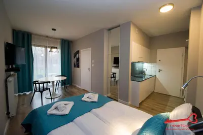 a bedroom with a bed and a table and a kitchen at Apartments Nearto Old Town Rakowicka in Kraków