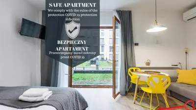a bedroom with a bed and a table and yellow chairs at Apartments Nearto Old Town Rakowicka in Kraków