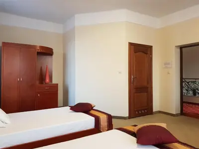 a bedroom with two beds and a wooden cabinet at Rezydencja Pod Zegarem in Trzebinia