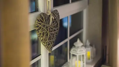 a heart hanging from a window next to a lantern at Main Street Apartments in Kraków