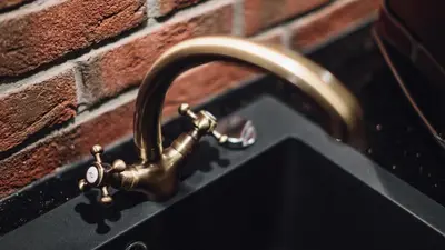 a bronze water tap on a brick wall at Main Street Apartments in Kraków