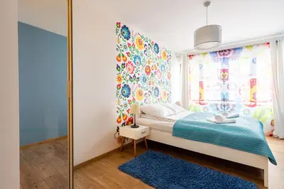 a bedroom with a bed with a blue rug and a window at Apartments Kremer Cracow in Kraków