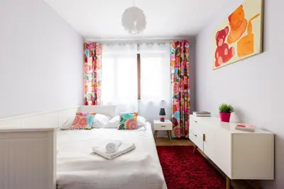 a white bedroom with a bed and a window at Apartments Kremer Cracow in Kraków