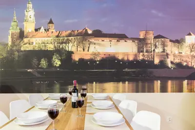 a table with glasses of wine and a castle at Apartments Kremer Cracow in Kraków