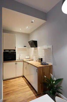 a kitchen with white cabinets and a black appliance at Gertrudy Old Town Apartments in Kraków