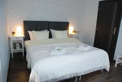 a bedroom with a large white bed with two towels on it at 7th Room Guest House in Oświęcim