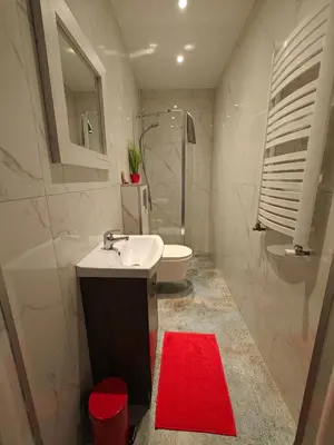 a bathroom with a white sink and a red rug at 7th Room Guest House in Oświęcim