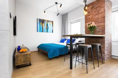 a living room with a bed and a table and chairs at Lofts Cracow Apartments - City Center in Kraków