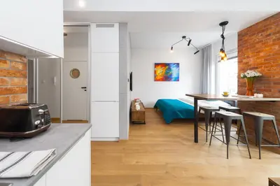 a kitchen and a living room with a table and chairs at Lofts Cracow Apartments - City Center in Kraków