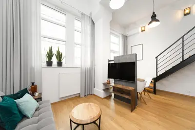 a living room with a couch and a tv at Lofts Cracow Apartments - City Center in Kraków