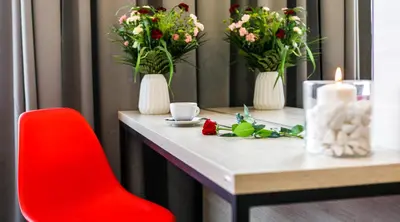 a table with flowers in vases and a red chair at Happy Apartments in Kraków