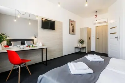 a bedroom with a bed and a desk and a red chair at Happy Apartments in Kraków