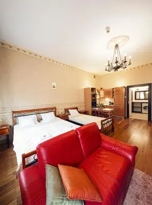 a living room with a red couch and a bed at Calliope Apartments in Kraków