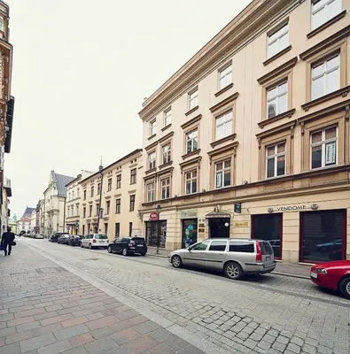 a city street with cars parked in front of buildings at Calliope Apartments in Kraków
