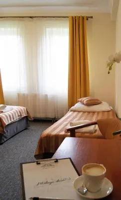 a room with two beds and a table with a cup of coffee at Salis Resort in Wieliczka